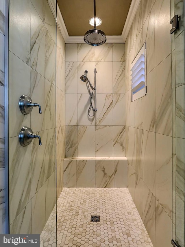 bathroom with ornamental molding and a tile shower