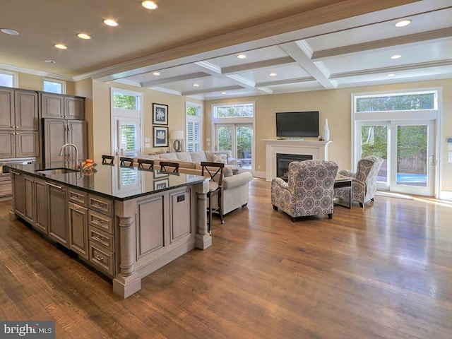 kitchen with a center island with sink, paneled built in fridge, dark hardwood / wood-style floors, coffered ceiling, and sink