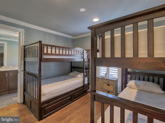 bedroom with ornamental molding, light hardwood / wood-style floors, and connected bathroom