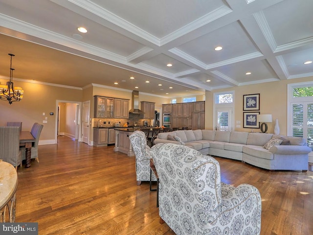 living room with hardwood / wood-style floors, coffered ceiling, a chandelier, and ornamental molding