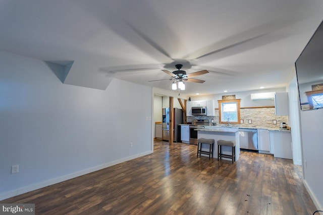 kitchen featuring a kitchen breakfast bar, dark hardwood / wood-style flooring, tasteful backsplash, stainless steel appliances, and white cabinets