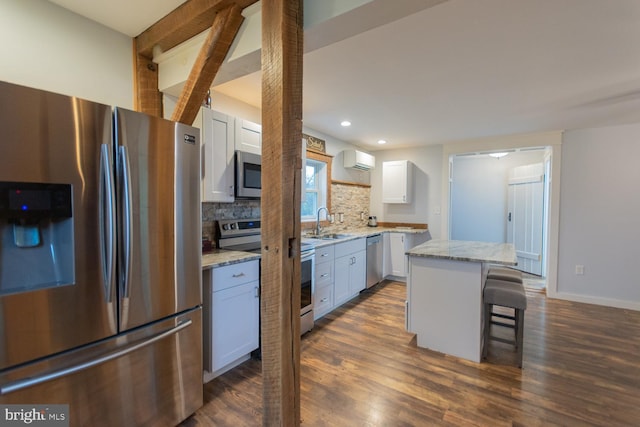 kitchen featuring appliances with stainless steel finishes, a wall unit AC, dark wood-type flooring, a center island, and white cabinetry