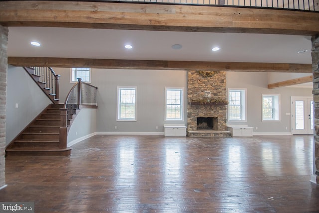 unfurnished living room featuring a wealth of natural light, a fireplace, and dark wood-type flooring