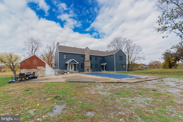 rear view of house with a patio and a lawn