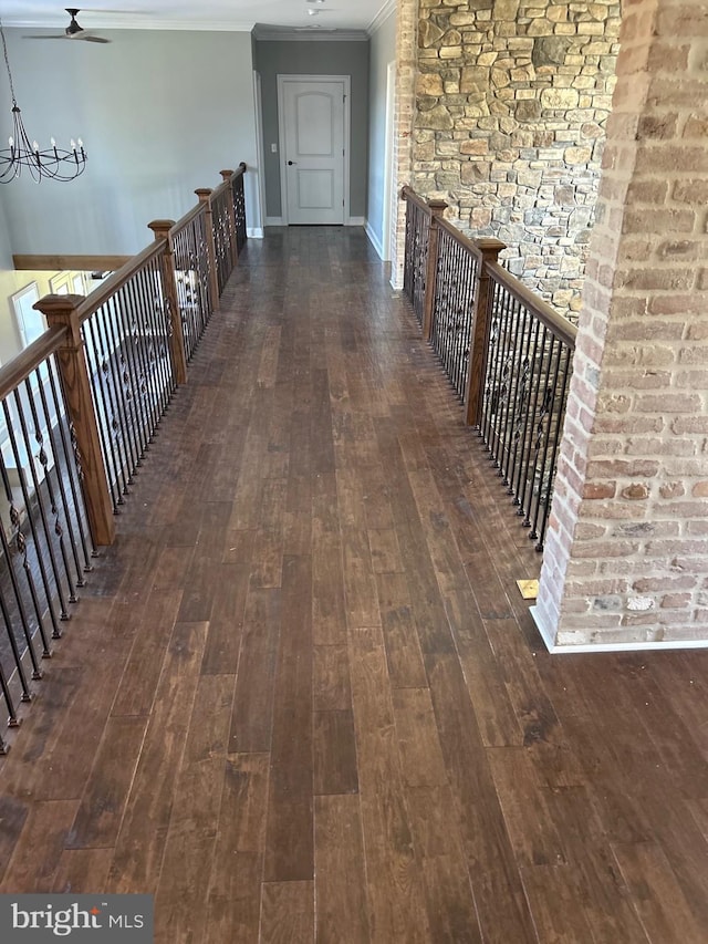 corridor with ornamental molding, dark hardwood / wood-style floors, and a notable chandelier