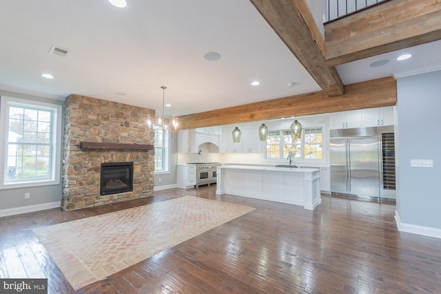 unfurnished living room with a fireplace, beam ceiling, dark hardwood / wood-style flooring, and sink