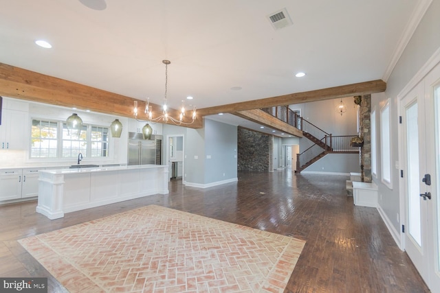 kitchen with white cabinetry, a center island, hanging light fixtures, built in refrigerator, and crown molding