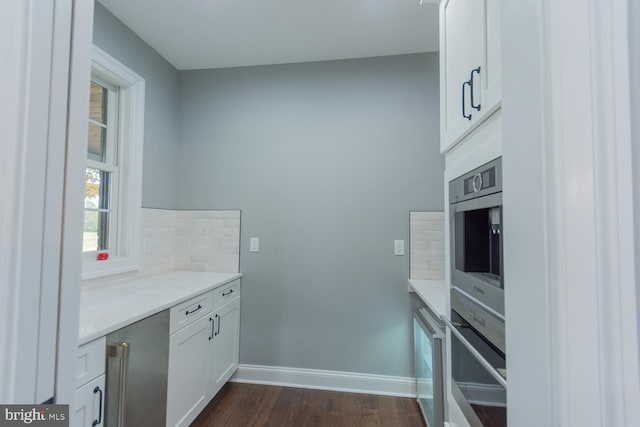 kitchen featuring white cabinets, backsplash, stainless steel oven, and dark wood-type flooring
