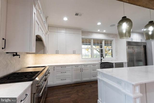 kitchen featuring dark hardwood / wood-style flooring, white cabinets, pendant lighting, and high end appliances