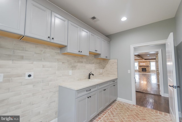 kitchen with sink, light stone countertops, backsplash, and light hardwood / wood-style flooring