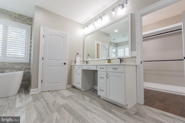 bathroom with a washtub, wood-type flooring, and vanity
