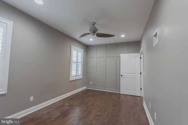 unfurnished bedroom with ceiling fan and dark wood-type flooring