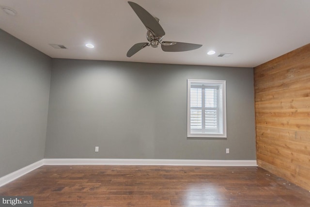 spare room with wood walls, dark hardwood / wood-style floors, and ceiling fan