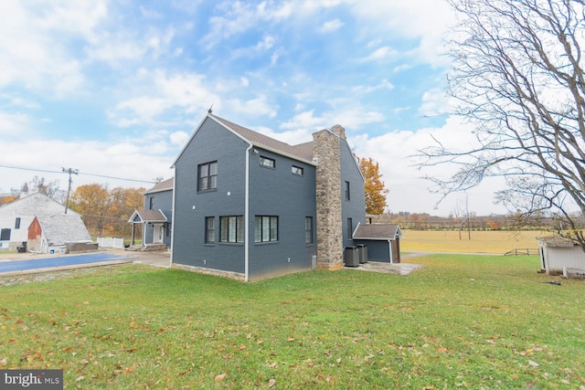 rear view of property with a patio, central air condition unit, and a lawn
