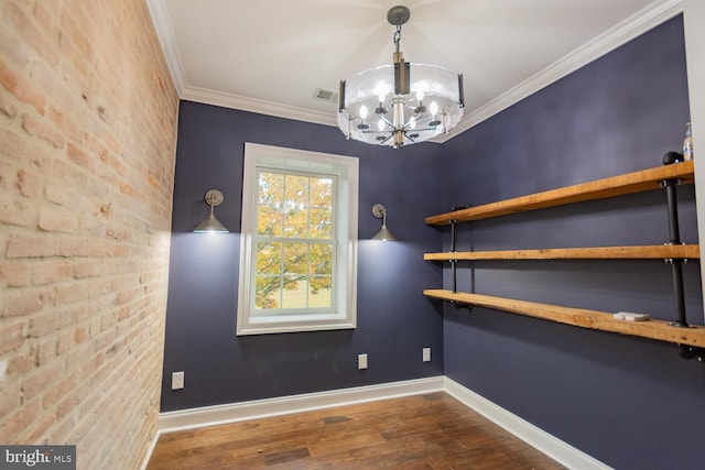 unfurnished dining area featuring wood-type flooring, crown molding, brick wall, and a chandelier