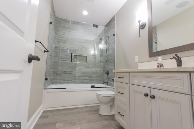 full bathroom featuring shower / bath combination with glass door, vanity, and toilet