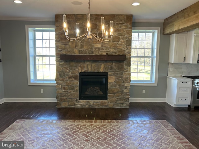 unfurnished living room featuring a stone fireplace, crown molding, dark hardwood / wood-style flooring, and a healthy amount of sunlight