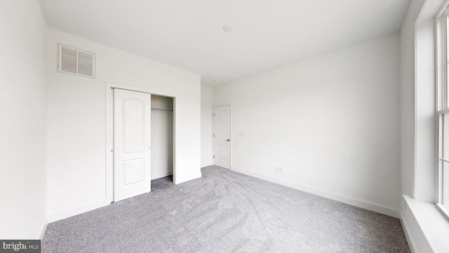 unfurnished bedroom featuring a closet and light colored carpet