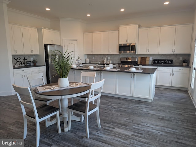 kitchen featuring white cabinets, a center island with sink, stainless steel appliances, and dark wood-type flooring