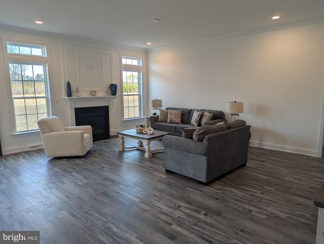 living room with crown molding, dark wood-type flooring, and a wealth of natural light