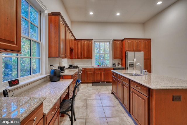 kitchen featuring plenty of natural light, stainless steel refrigerator with ice dispenser, sink, and light tile floors