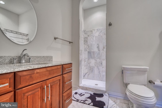 bathroom featuring toilet, tile flooring, a tile shower, and vanity