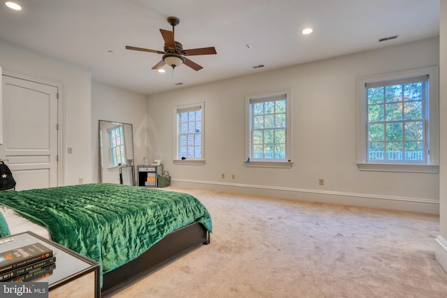 carpeted bedroom with multiple windows and ceiling fan