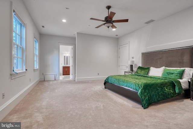 bedroom featuring light carpet, ceiling fan, and ensuite bathroom