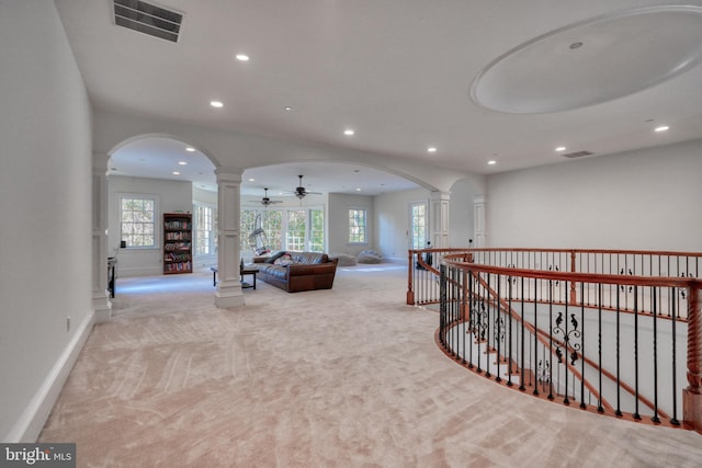 hall with ornate columns and light colored carpet