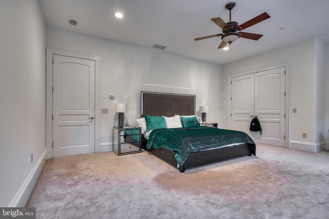 bedroom with ceiling fan, light colored carpet, and a closet