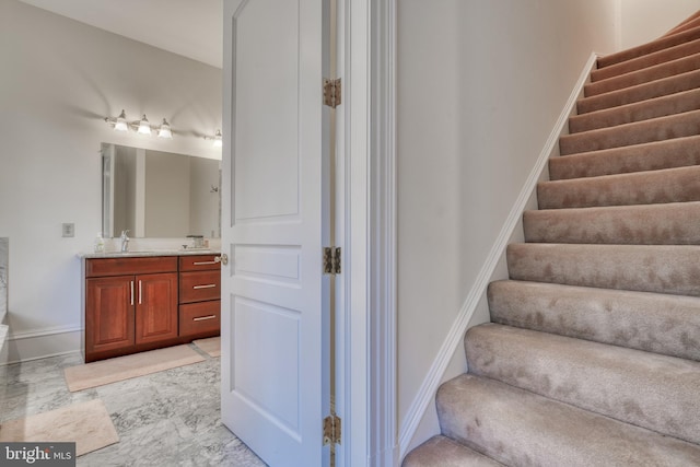 stairway featuring sink and light tile floors