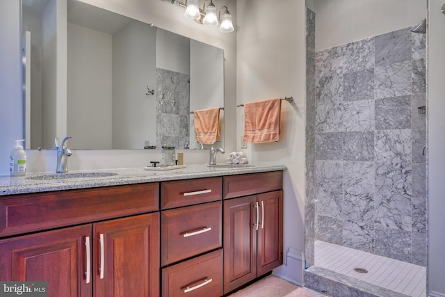 bathroom featuring dual bowl vanity and tiled shower