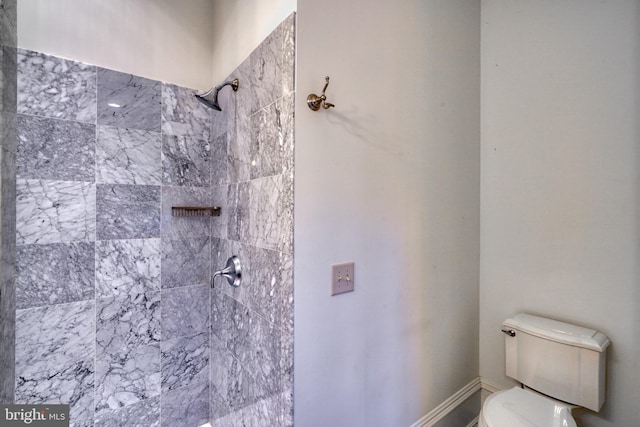 bathroom featuring a tile shower and toilet