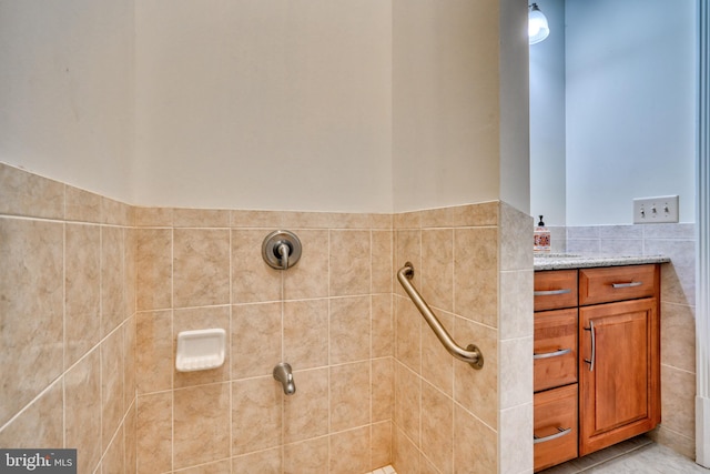 bathroom with a shower, tile walls, tile flooring, and vanity