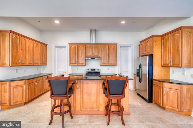 kitchen with light tile floors, appliances with stainless steel finishes, a kitchen bar, and an island with sink