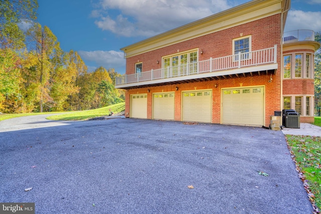 view of front facade featuring a balcony, central AC, and a garage