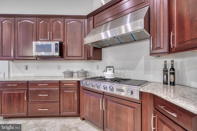 kitchen with light stone countertops, appliances with stainless steel finishes, light tile floors, and wall chimney exhaust hood