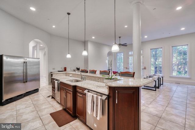 kitchen with ceiling fan, sink, stainless steel appliances, light stone counters, and pendant lighting