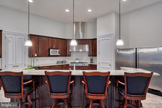 kitchen featuring hanging light fixtures, stainless steel appliances, and a center island with sink