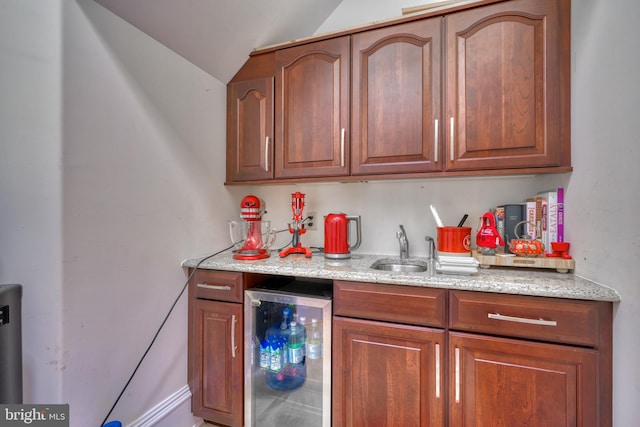 kitchen featuring light stone counters, wine cooler, sink, and lofted ceiling