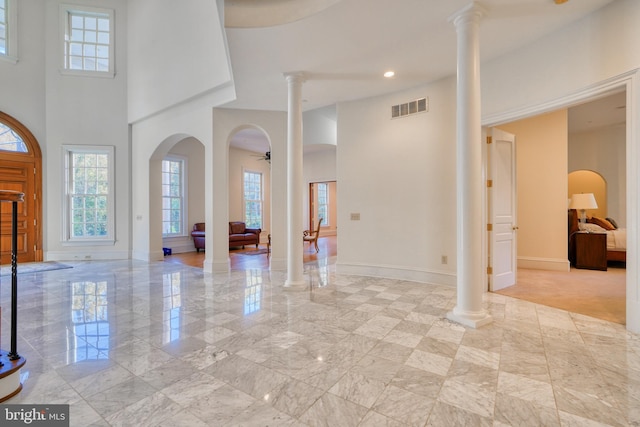 foyer with ceiling fan, light tile floors, and decorative columns