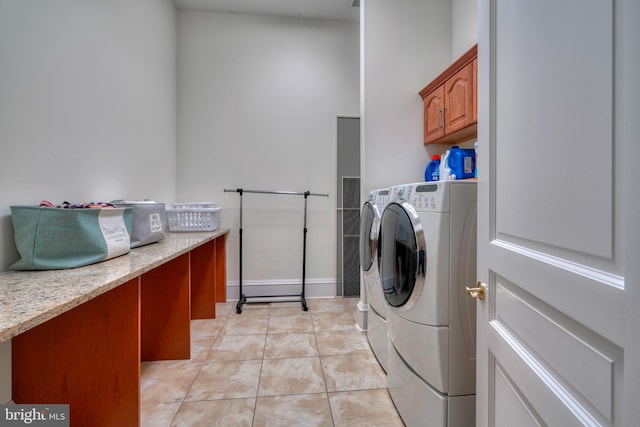 laundry room featuring light tile flooring, cabinets, and washer and clothes dryer