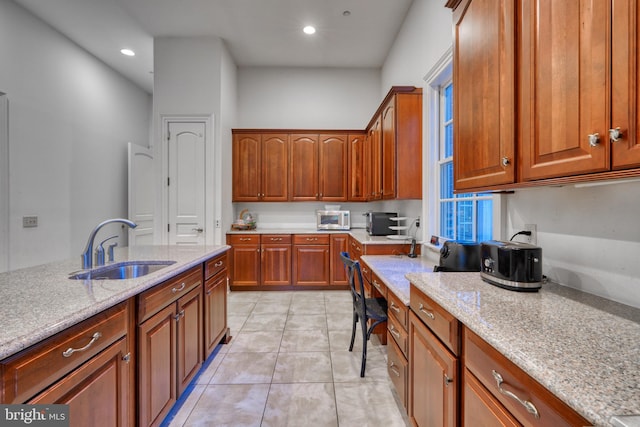 kitchen featuring light tile floors, sink, and light stone countertops