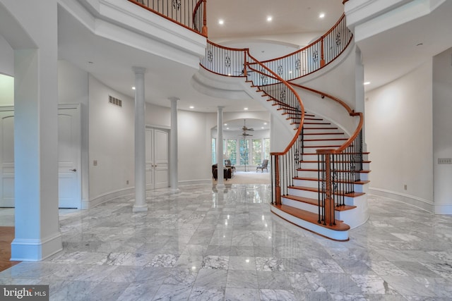 entryway featuring ceiling fan, a towering ceiling, and ornate columns