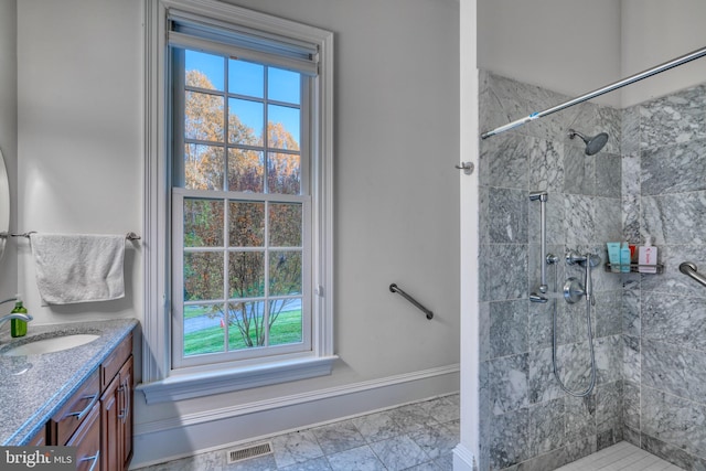 bathroom with tile floors, a tile shower, and vanity