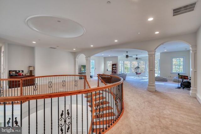 corridor featuring decorative columns and light colored carpet