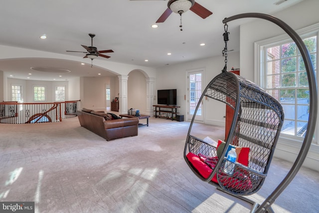 carpeted living room featuring ceiling fan, a wealth of natural light, and ornate columns