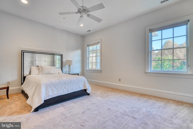 bedroom with light colored carpet, ceiling fan, and multiple windows