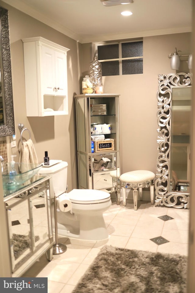 bathroom with tile patterned floors, toilet, ornamental molding, and sink