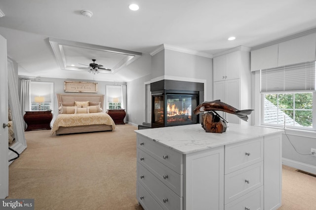 bedroom featuring ceiling fan, a multi sided fireplace, a raised ceiling, light colored carpet, and ornamental molding